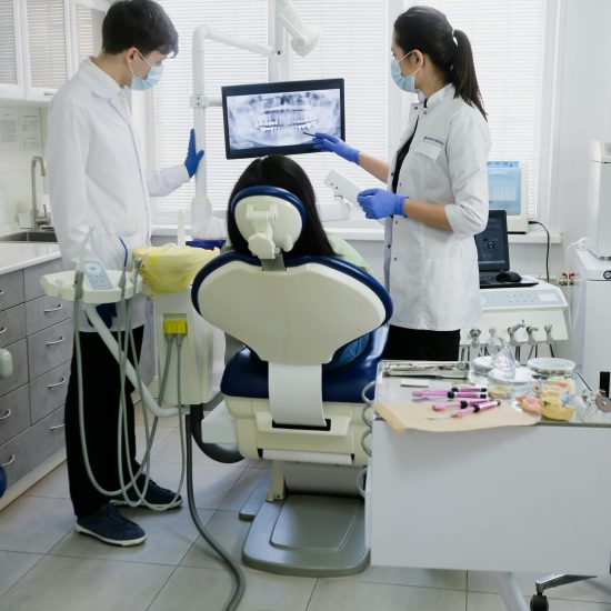 Professional dental team examining patient with advanced equipment in a modern clinic.